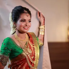 A candid moment with a happy bride. Her look features a traditional South Indian makeup style with gold jewelry, a neat updo with flowers, and a bright smile that shows her joy.