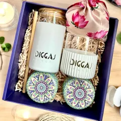 A sustainable and stylish corporate hamper designed for Diggaj Realty. It includes a branded borosilicate sipper and glass, decorative tin jars with treats, and a pichwai potli, all arranged in a custom purple box.