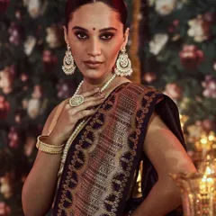 The epitome of bridal grace. This image captures the intricate zari work on the pallu of a deep blue Banarasi silk saree, a classic choice for wedding ceremonies and receptions, paired with traditional pearl jewelry.