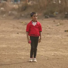 The future of cricket starts here. A young girl, one of our youngest players, stands ready on the field during our anniversary match.