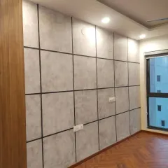 An industrial-style accent wall with a concrete texture finish, sectioned into large panels with clean black lines to create a sophisticated, modern look in a bedroom.