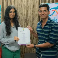A student proudly receives her Trinity College London graded exam certificate from her teacher.