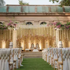 The wedding aisle, lined with elegant seating and leading to a mandap draped in fragrant rajnigandha strings, creates a path of classic, serene, and timeless beauty. This setup was designed for an outdoor wedding at a heritage venue in Mumbai.