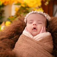 A detailed close-up of a sleeping newborn's face, with tiny hands resting on their cheeks. We focus on capturing these innocent, fleeting expressions and poses that you will cherish for years to come.