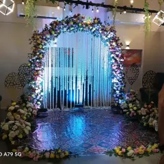 A beautiful floral arch decorated with hanging strings of white flowers. The blue uplighting creates a magical effect, making it a stunning centerpiece or entryway for an evening gala or ceremony.