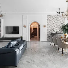 This expansive living and dining area is a perfect example of modern luxury. We used a foundation of white marble flooring and classic wall mouldings, then layered in a deep blue leather sofa and elegant chandeliers to create a space that feels both grand and welcoming.