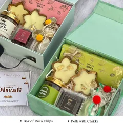 Our elegant twin box hamper is perfect for Diwali. This one is filled with Roca chips, a jar of trail mix, dragees, chikki in a potli, and decorative urlis, making it a complete festive package.