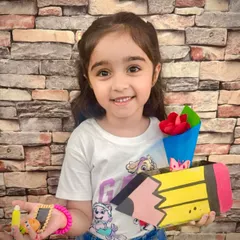A happy student holds up the pencil-shaped box and clay keychain she made for her teacher. Our Teacher's Day workshop is all about creating thoughtful, handmade gifts from the heart.