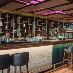 A full view of the main bar, showcasing the intricate suspended shelving, comfortable bar stools, and custom-paneled bar front, creating a sophisticated focal point.
