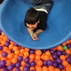 A cheerful face peeking out from the slide before plunging into the ball pit. This is the kind of pure, simple fun we love to provide.