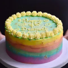 A vibrant rainbow birthday cake with a watercolour buttercream effect and delicate gold leaf flecks. This cheerful and colourful cake is a popular choice for bringing a splash of joy to any birthday party.