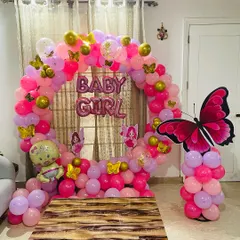 For this "Baby Girl" welcome party, I combined a circular balloon arch with a butterfly theme. The decoration uses pink, purple, and gold balloons, along with a large butterfly prop and baby-themed foil balloons.
