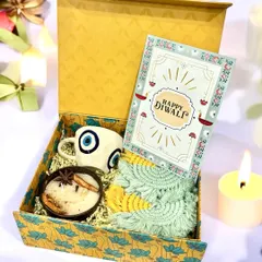 This hamper combines an evil eye mug, a coconut shell candle, and macrame coasters, all tied together with a personalized Diwali card. It's a perfect blend of trendy, sustainable, and traditional elements.
