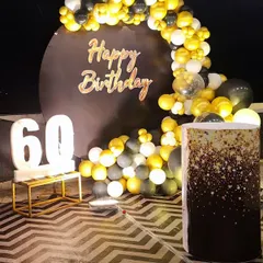 A closer look at the 60th birthday decor, highlighting the glittery cake stand that ties in with the black and gold theme. Every detail is planned to create a cohesive and elegant design.