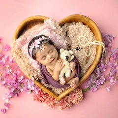 A newborn peacefully dreaming in a heart-shaped bowl, surrounded by soft pinks. This is the kind of timeless, gentle portrait I love to create in those magical first few days.