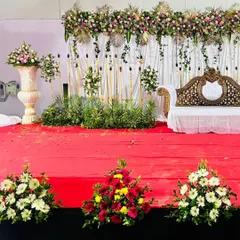 Here is a closer look at a simple yet beautiful reception stage. The focus is on the floral garland across the top, the elegant carved sofa, and the simple white curtain backdrop, showing that a clean design can be very effective.