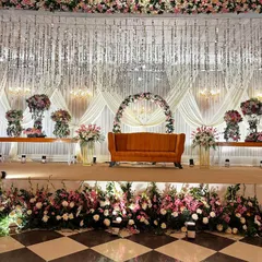 A closer view of the opulent reception stage. The intricate details of the hanging crystal strings, the floral arch, and the layered flower beds along the stage front are clearly visible.