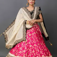 A model dressed in a vibrant pink and black lehenga with a cream-colored dupatta, captured in a classic pose for a bridal or festive wear catalog.