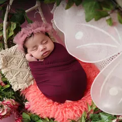 A close-up of the sleeping baby in the butterfly-themed setup. This angle highlights the delicate floral headband and the peaceful expression of the baby.