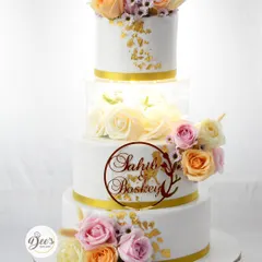 A wedding cake should be as timeless as your love story. This four-tier beauty features an illuminated acrylic section filled with roses, delicate sugar flowers, and touches of edible gold leaf for a truly showstopping centerpiece.