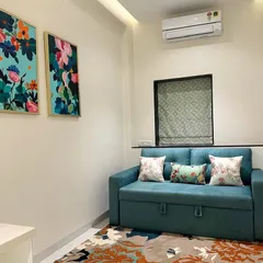 This cozy nook in the same South Mumbai residence features a teal sofa bed complemented by vibrant floral canvas art. The abstract rug ties the colors together, creating a lively yet sophisticated space.