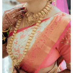 A detailed shot of a traditional South Indian bride's attire, focusing on her magnificent gold temple jewelry and silk saree.