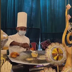 Our chefs in action at a live chaat counter. Here, a chef is preparing fresh Aloo Tikki Chaat on a hot tawa, ensuring every guest gets a plate made to their preference, right before their eyes.