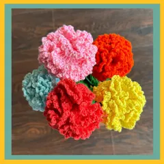 A top-down view of a colorful bunch of crochet carnations. I make these in a variety of colors like pink, red, yellow, orange, and light blue, each with fluffy, textured petals that look just like the real thing.
