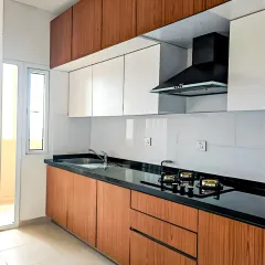 A simple yet elegant straight-line kitchen combining light wood base cabinets with clean white upper cabinets. The black granite countertop and built-in hob make this a practical and stylish solution, especially for smaller kitchen layouts.