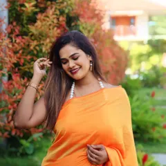 A client looking beautiful in a simple and elegant orange satin saree, perfect for a daytime event.