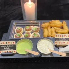 A platter of Mutton Galouti Kebabs and Fish Orley, perfect for a Diwali celebration. The card-themed labels and candle-lit presentation tie everything together for a festive cards night.