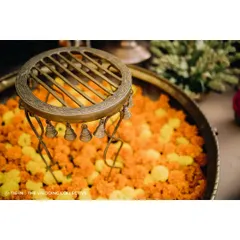 An antique brass stand with tiny bells, placed in a bowl of fresh marigolds. This small vignette from a Haldi ceremony showcases our love for combining traditional artifacts with fresh, vibrant florals to create beautiful textures.