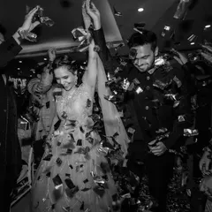 A classic black and white shot of the couple's entrance. The confetti shower and their happy expressions make for a timeless and celebratory photograph.
