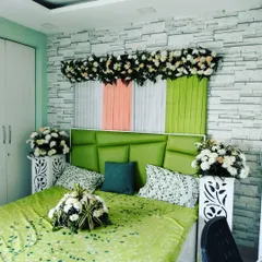A simple and elegant first-night room decoration. The headboard is decorated with drapes and flowers, and floral bouquets are placed around the room to create a fresh and romantic feel.