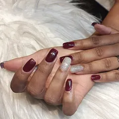 A perfect party-ready look. This manicure combines a rich, dark red polish with a sparkling silver glitter accent nail for a touch of glamour.