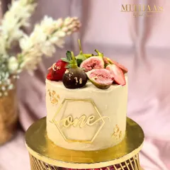 A delicate cake for a first birthday celebration. This vanilla bean cake is topped with fresh figs and strawberries, with a gold-dipped fig and a custom "one" cake topper for an elegant touch.