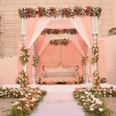 This elegant mandap features soft peach draping, classic silver pillars, and lush floral arrangements. The design creates an intimate and romantic setting, perfect for a day wedding ceremony.