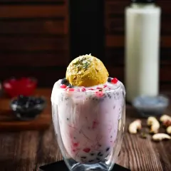 A refreshing falooda-inspired boba drink with a scoop of mango ice cream. The contrast between the dark background and the colorful drink makes it look incredibly tempting.