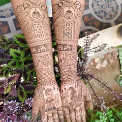 A full bridal mehendi design that goes up to the elbows, showcasing traditional Indian artistry. The palms feature classic dulha-dulhan (bride and groom) figures, while the arms are filled with intricate patterns, including elephants, kalash motifs, and delicate jaal work, all done with natural henna.