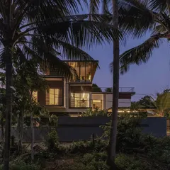 An aerial view and a dusk shot of the Mango Tree Yard residence in Thrissur, showing the pavilion-style layout nestled within a lush, tropical landscape.
