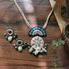 A beautiful handmade necklace set in blue and white, featuring intricate mirror work and kowri shell details. The matching earrings have delicate ghungroo bells that jingle softly.