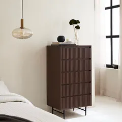 The tallboy chest of drawers placed in a serene bedroom context. The shot highlights its verticality and slim profile, making it suitable for various room sizes.