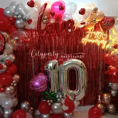 A focused shot of the anniversary balloon arch, showing the mix of red, white, and silver balloons, transparent balloons with hearts inside, and 'Love' foil letters.