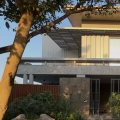 The warm evening light catches the textured facade of 'STILL HOME'. The interplay of solid and void, light and shadow, and hardscape and softscape creates a dynamic yet calming exterior.