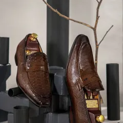 To emphasize the texture of these brown ostrich leather loafers, I used a dark, structured setup with geometric blocks and a bare branch. This creates a masculine and modern feel, focusing on the shoe's craftsmanship.