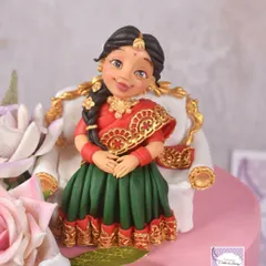 This was my first time creating a cake for a half-saree function. The design features a detailed figurine of the young lady in her traditional attire, complete with intricate gold work on her langa voni, seated on an elegant miniature sofa.
