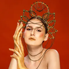 A striking editorial shot of a model with golden hands and a dramatic headpiece, looking directly at the camera. This type of powerful, artistic imagery is designed to be unforgettable and make a strong brand statement.