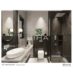 A detailed view of the washroom, highlighting the sleek, wall-mounted fixtures and the vessel sink. The combination of dark and light marble, along with a frameless glass shower partition, contributes to a clean, uncluttered, and highly modern aesthetic.