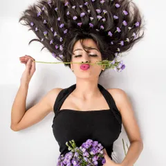 A playful variation of the 'Wild Lavender' series. The model lies on her back, puckering her lips towards a flower stem, adding a touch of whimsy to this creative floral concept.