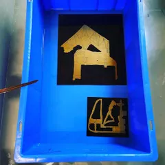 Etched plates submerged in a ferric chloride bath. This alchemical part of the printmaking process, where acid bites into the metal to create the image, is a powerful metaphor for how ideas are given permanent form.